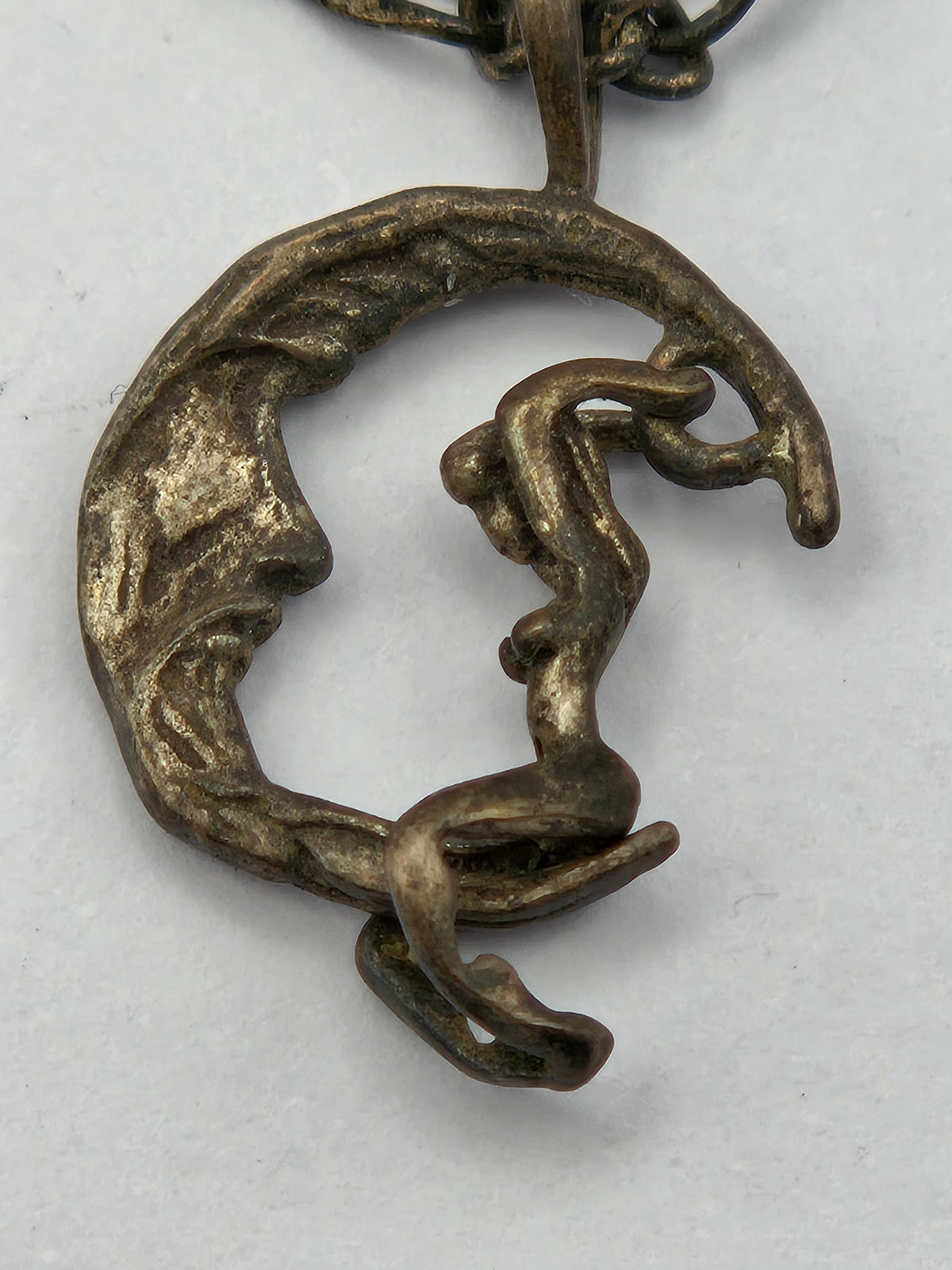Sterling silver pendant of a moon rider on a crescent moon with accompanying chain.