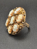 Domed cocktail ring with seven carved shell cameos in a gold-filled filigree setting.