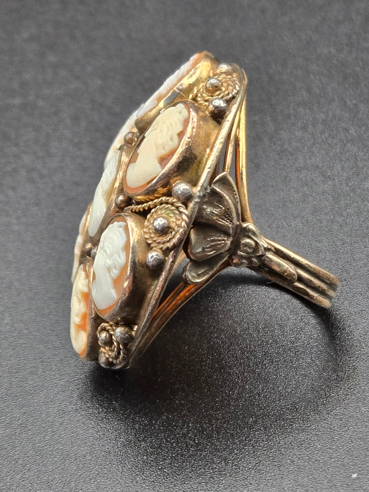 angled close-up showing carved profiles and filigree bezel