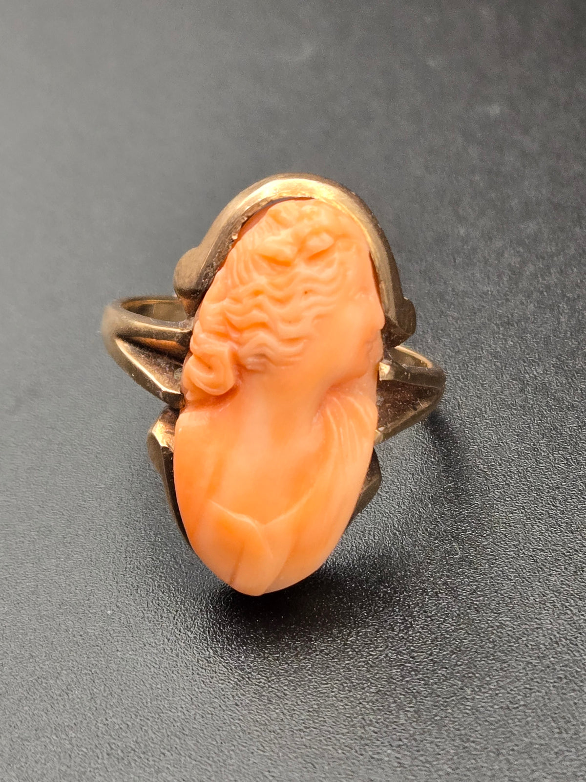 close-up of carved salmon-pink coral cameo set in 10k gold bezel