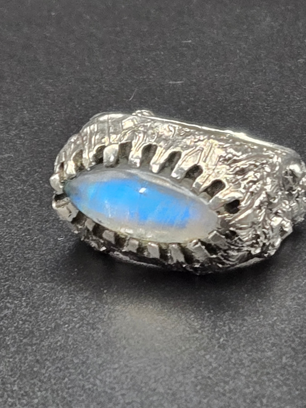 angled shot highlighting textured lava band and moonstone cabochon