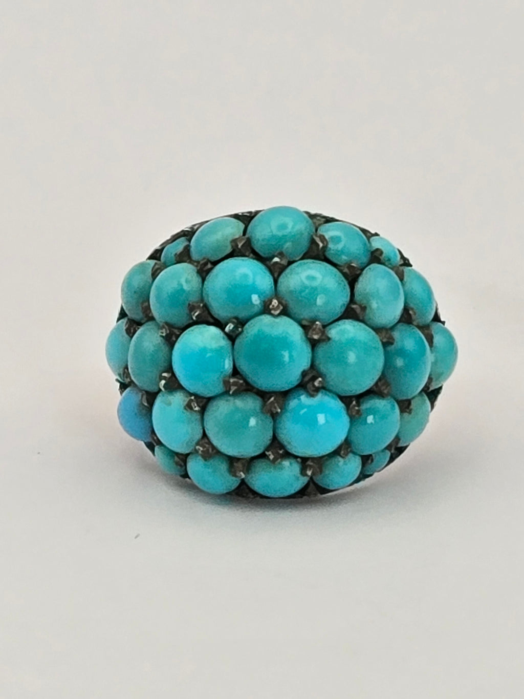 angled view of domed Persian turquoise set in silver prongs