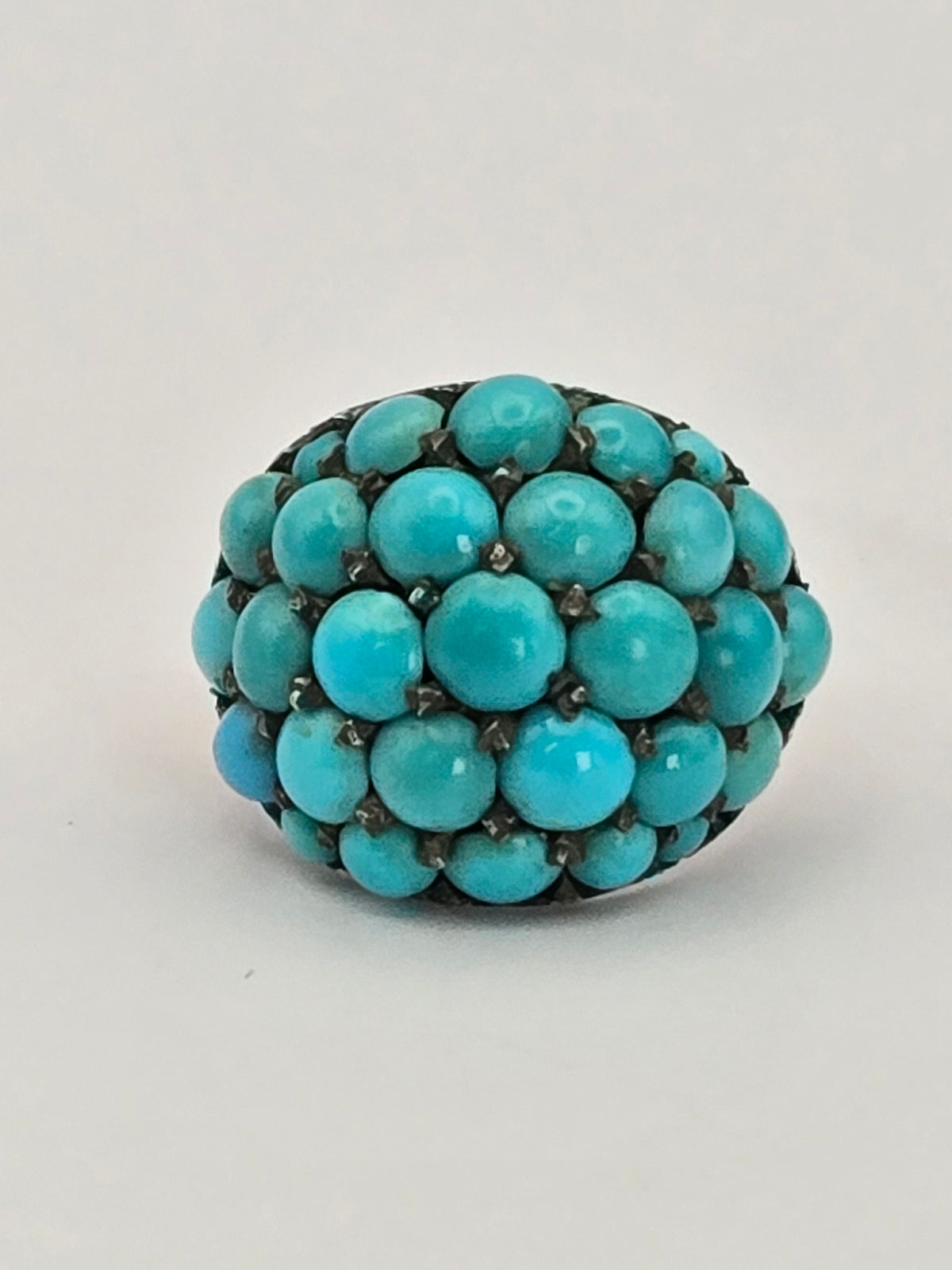 angled view of domed Persian turquoise set in silver prongs
